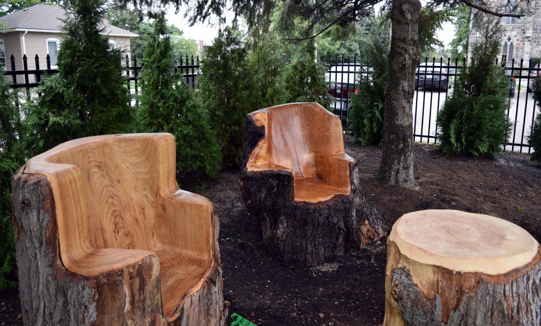 two chairs carved out of a tree trunk sit around a tree trunk table in a peaceful garden