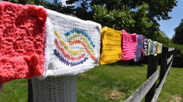 Several knitted swatches bearing the sensity logo are lined up on a fence
