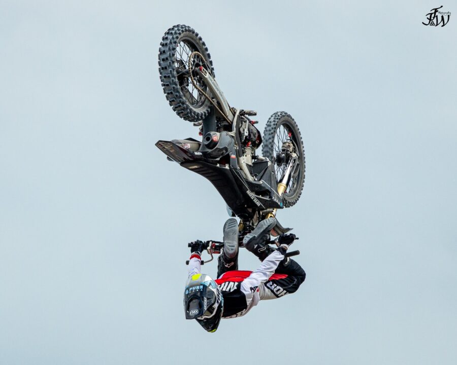 A person on a dirtbike is upside down in the air