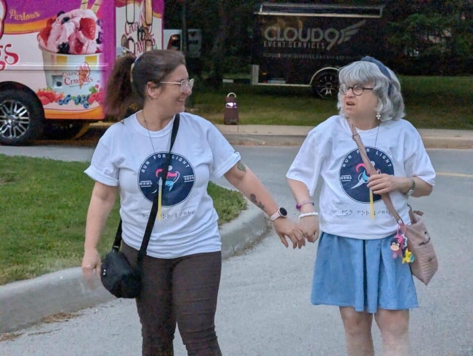 Une personne sourde et aveugle marche à l'extérieur aux côtés de son accompagnateur.